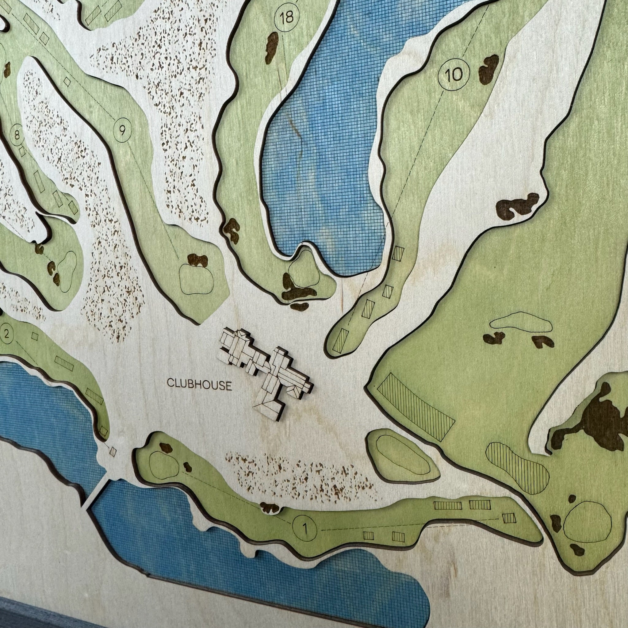 Golf course layout with clubhouse and numbered holes on a wooden plaque